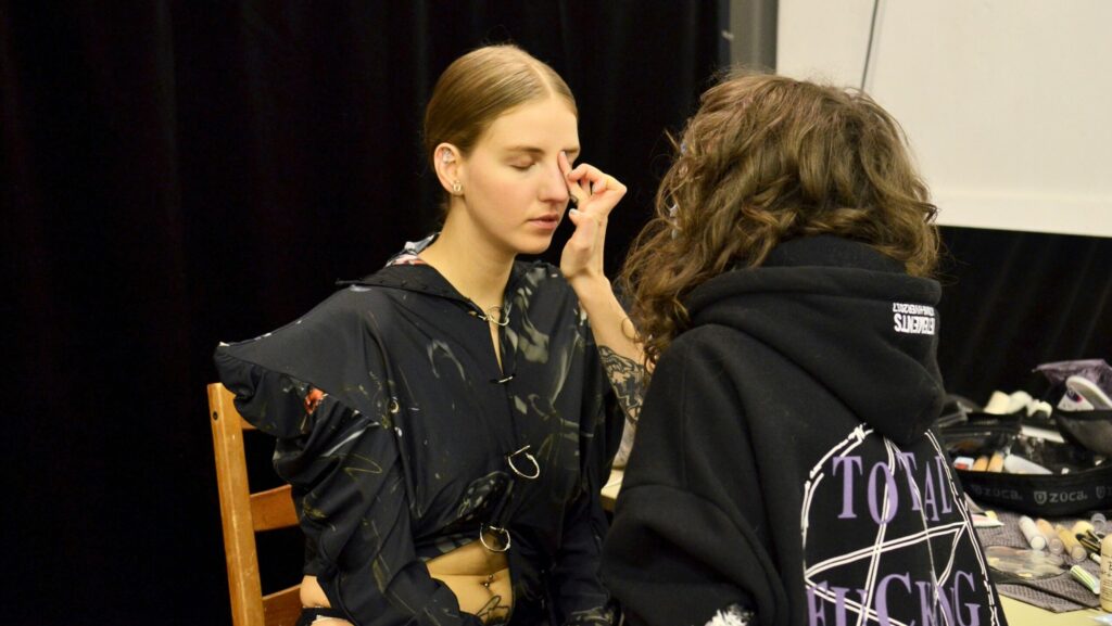 Female stylist applying foundation on face of model during preparation for photo session